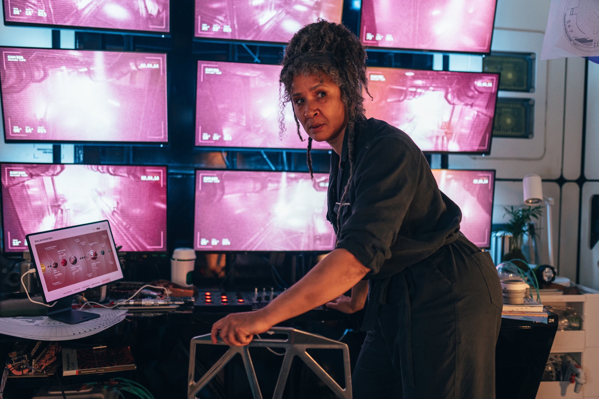 A woman in front of a bank of screens