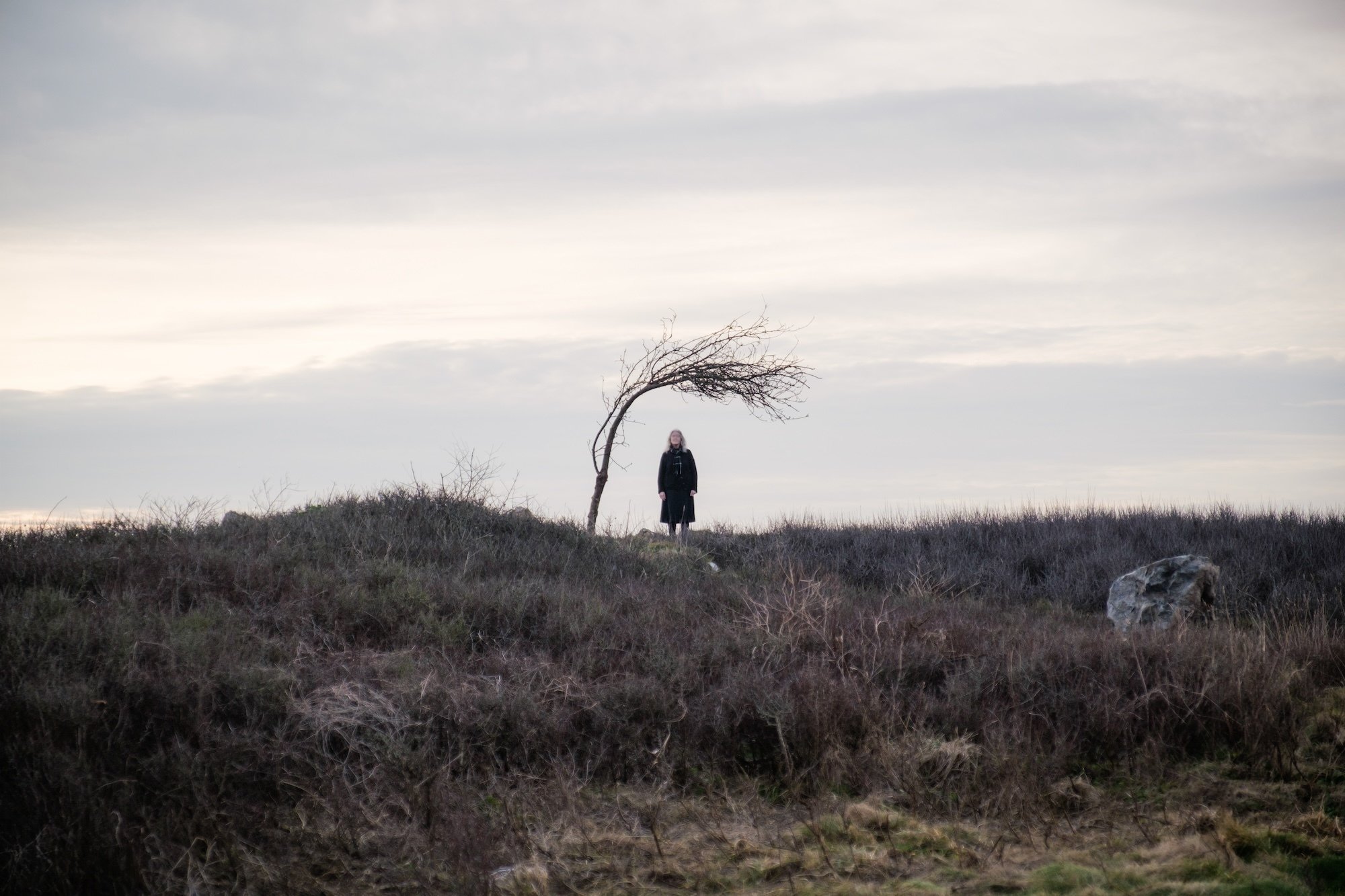 An old woman standing under a tree at a distance of 73 yards