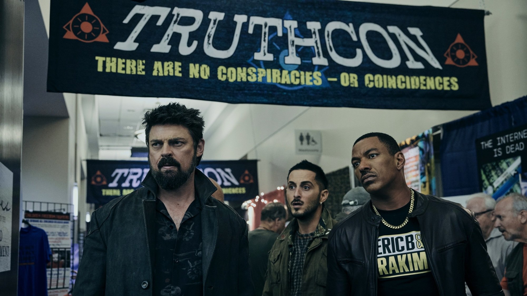 Butcher, Frenchie, and Mother's Milk walk under a black banner that reads, "TruthCon: There are no conspiracies — or coincidences."