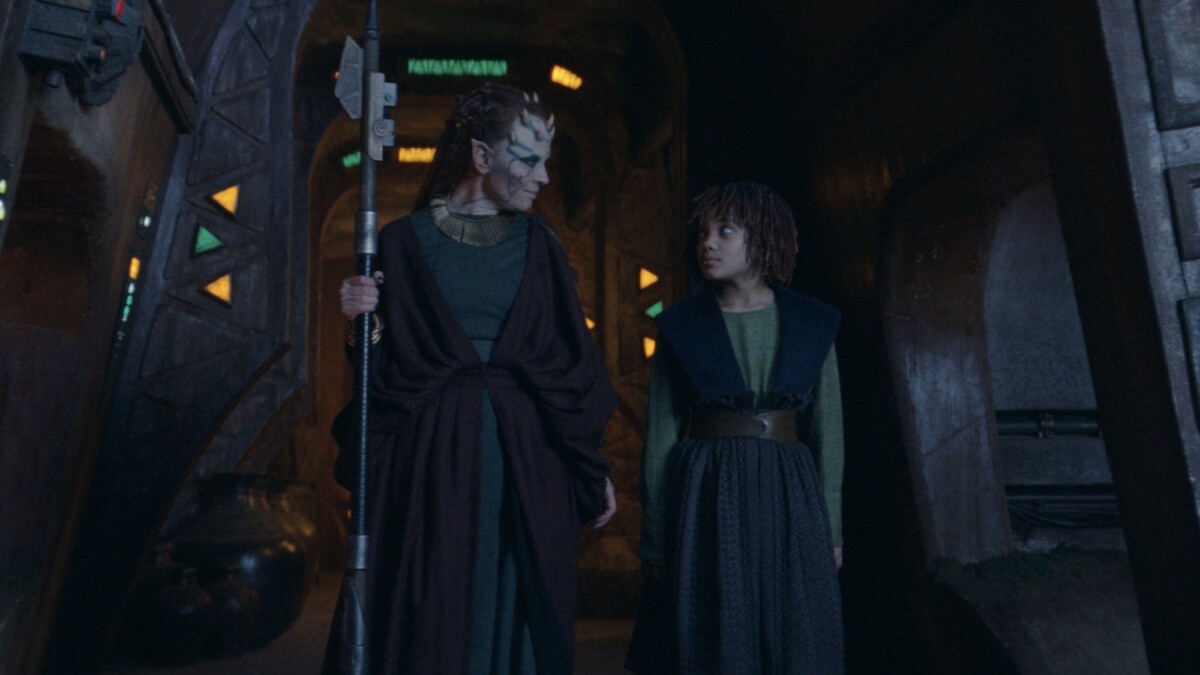 Mother Koril and young Mae walk through the halls of the fortress on Brendok.