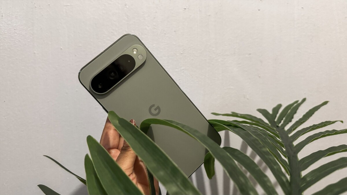 The Google Pixel 9 Pro XL being held amidst the leaves of a plant.