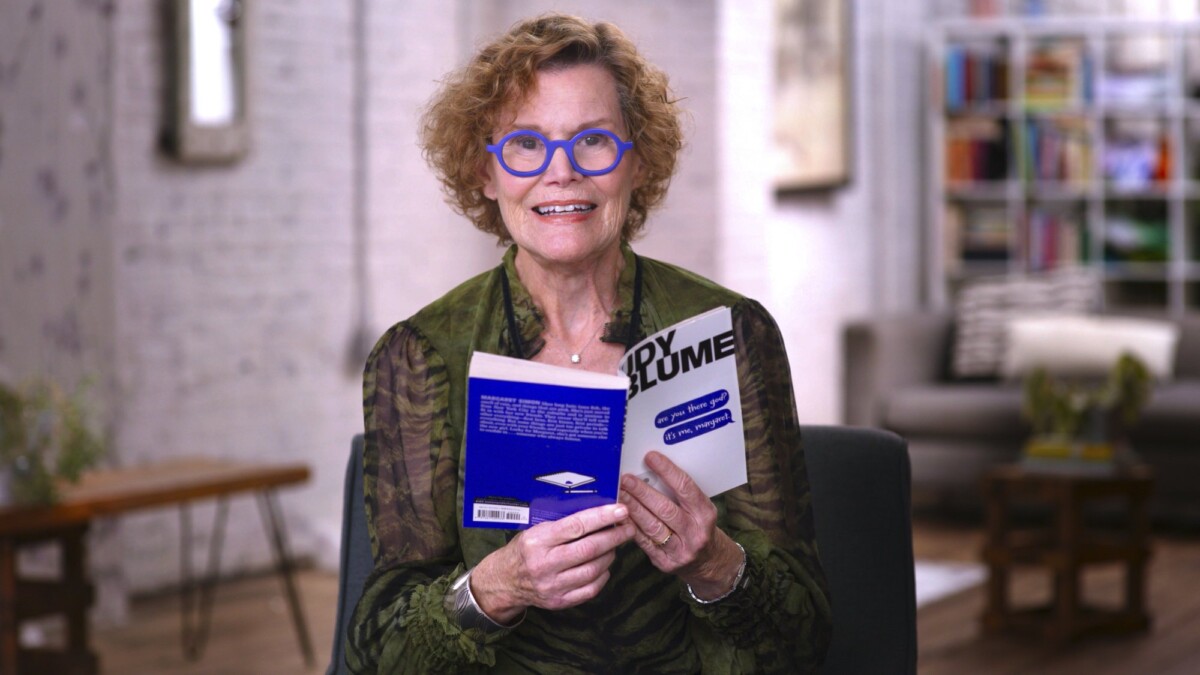 Judy Blume sits in a chair, reading from "Are You There God? It's Me, Margaret."