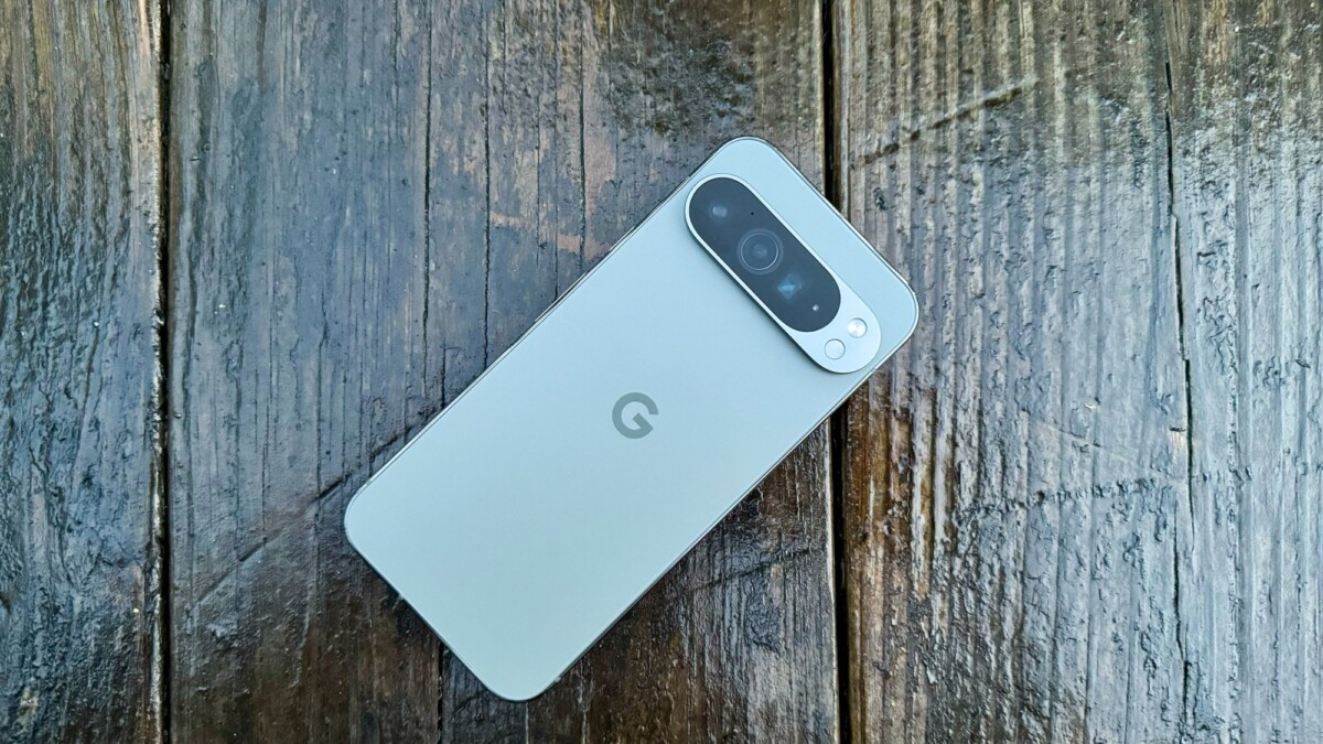 The Google Pixel 9 Pro XL on a wooden surface, screen facing down so the back camera is visible.