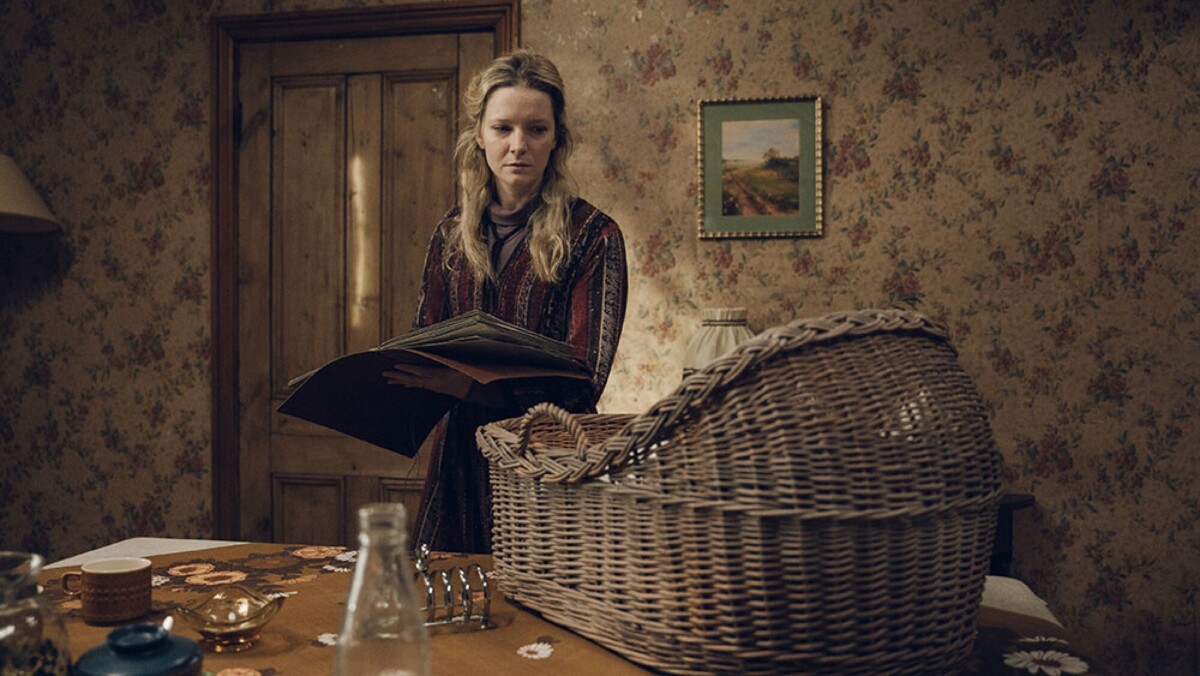 A woman stands looking at a crib.