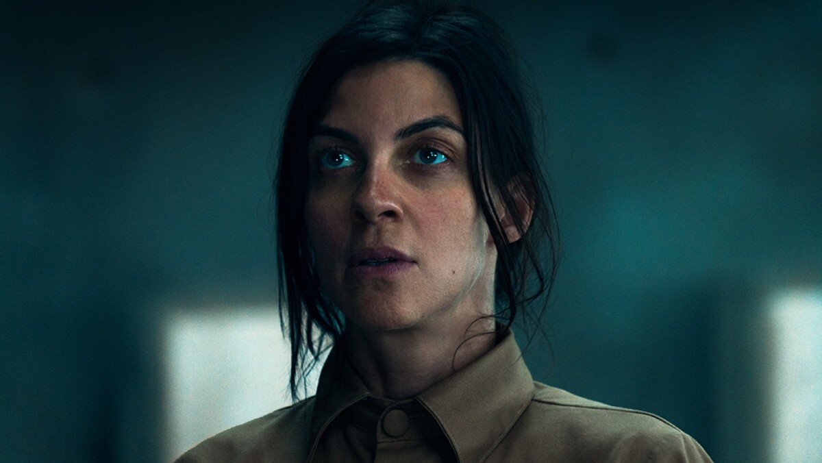 A close-up of a woman standing in a concrete room.