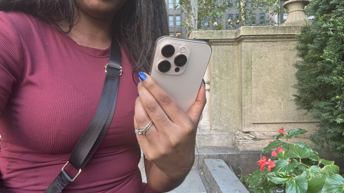 Woman holding iPhone 16 Pro in a park