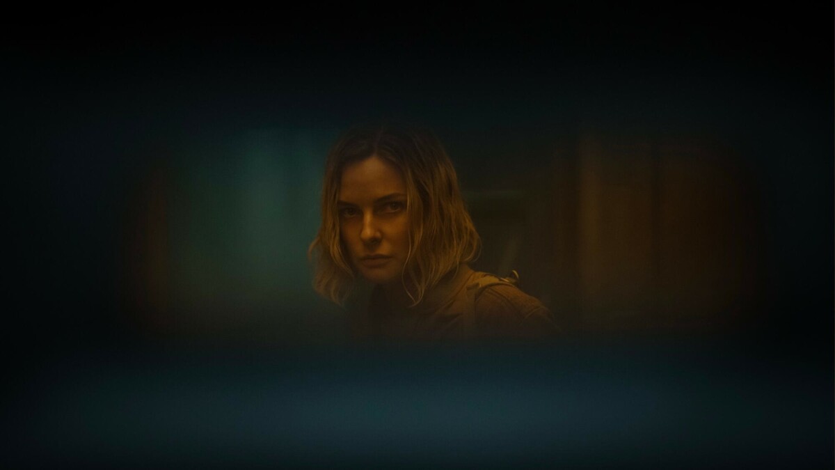 Rebecca Ferguson as Juliette Nichols in "Silo" looks through a slot on a door.