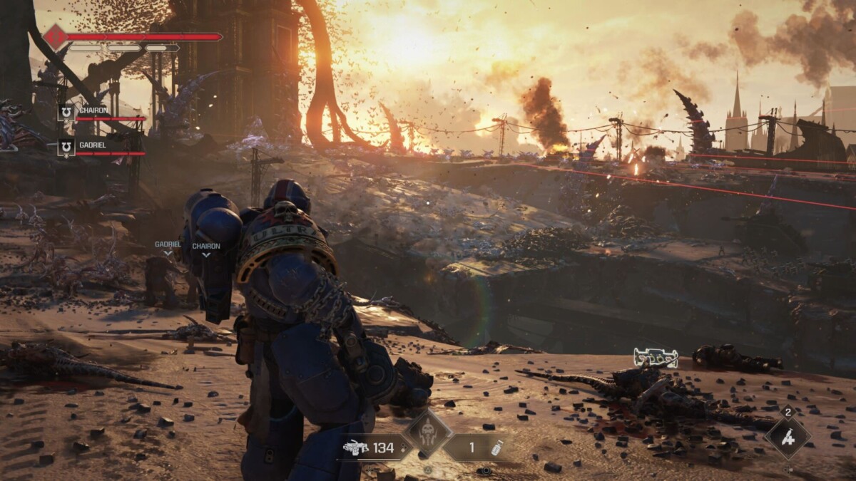 In-game action screenshot featuring a Space Marine in Ultramarine armor, overlooking a battlefield with Tyranid enemies in the distance during sunset.