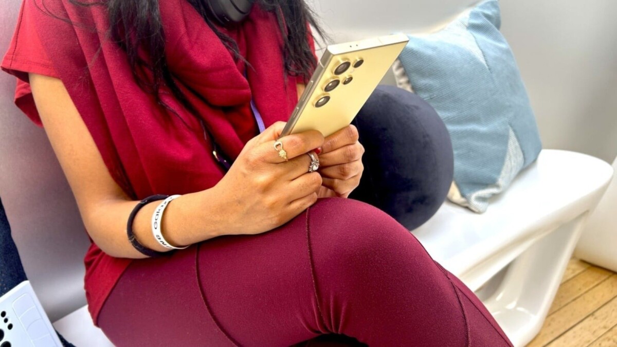 Woman sitting down holding the Samsung Galaxy S24 Ultra