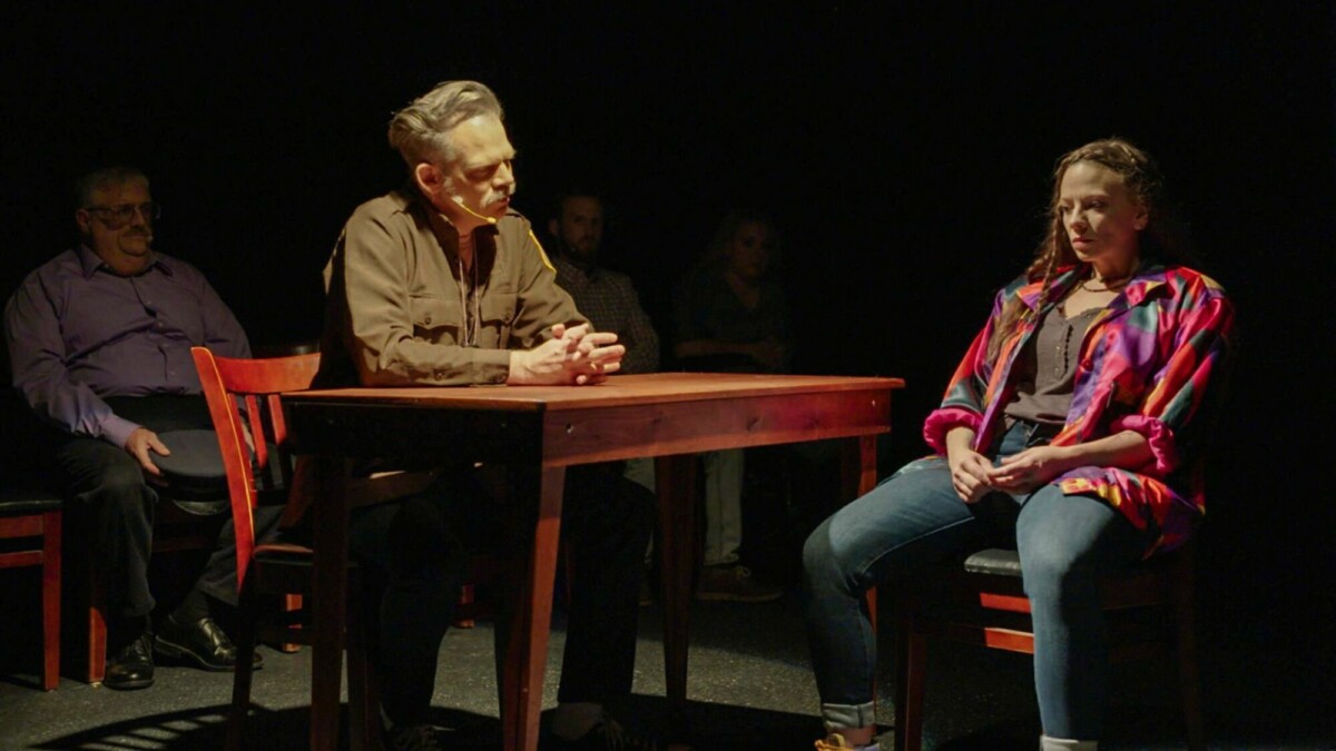 Theater actors re-enact a police interrogation on stage. 