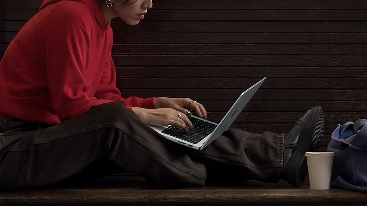 person sitting outside using macbook on their lap