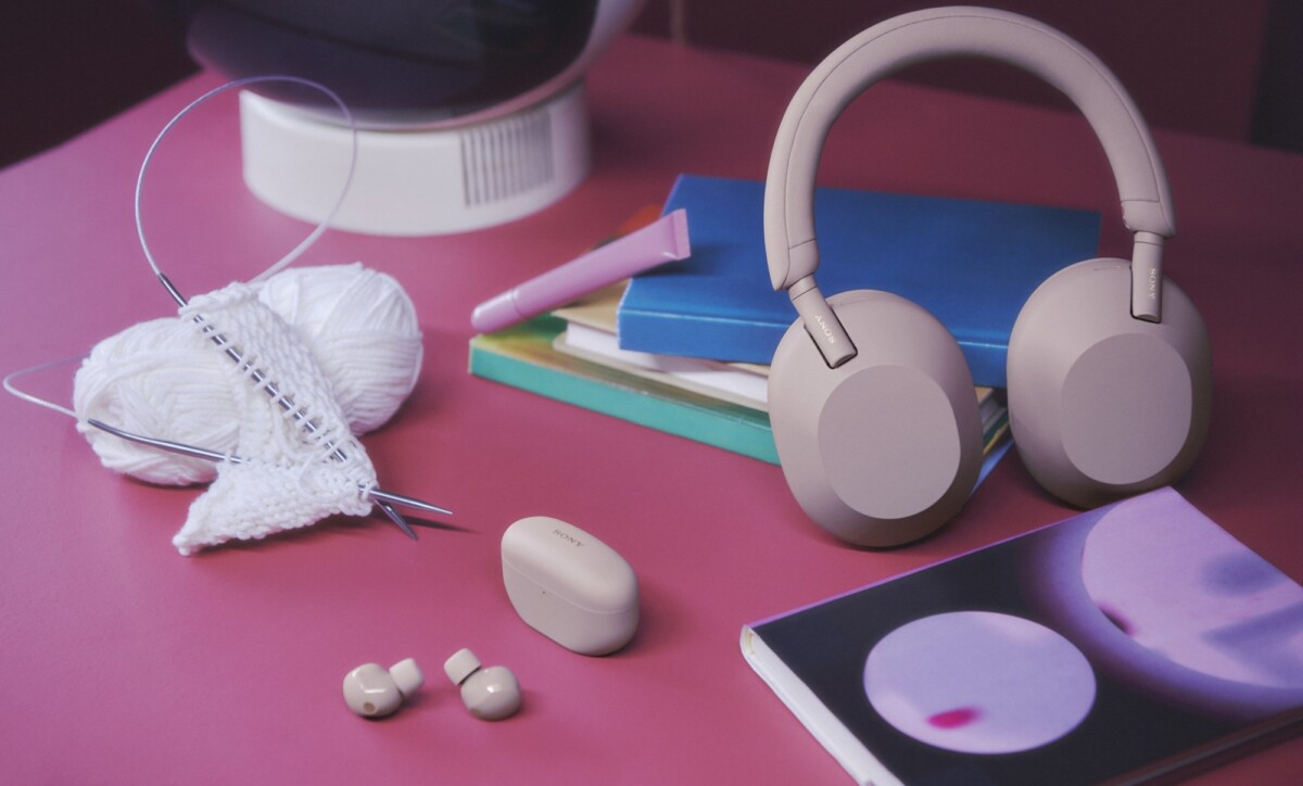 A pair of Sony headphones on a table with crocheting needles and yarn. 