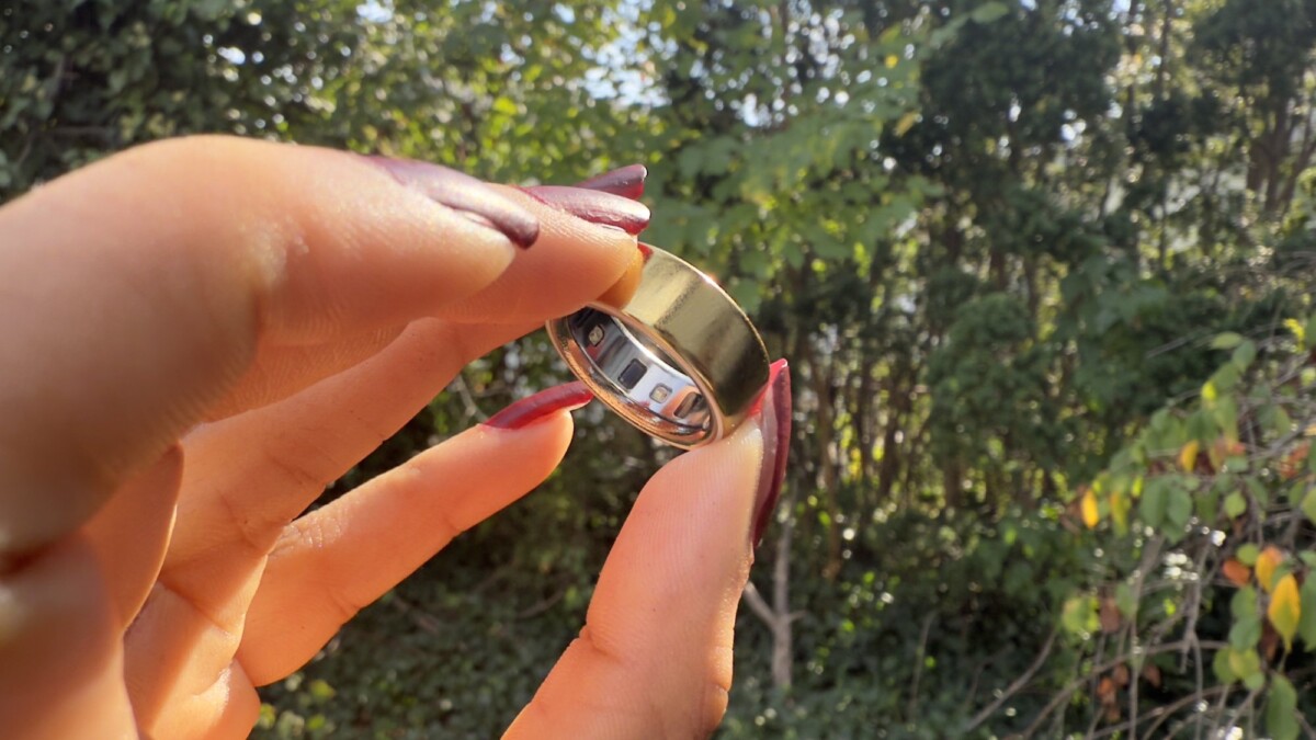 Oura Ring 4 between someone's fingers with leafy background