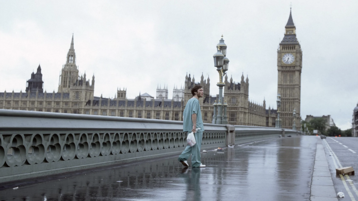 A man walks over a bridge in London holding a plastic bag.