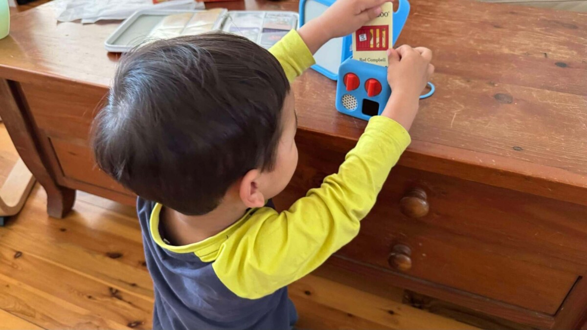 A toddler inserting a "Dear Zoo" card into the Yoto Mini.