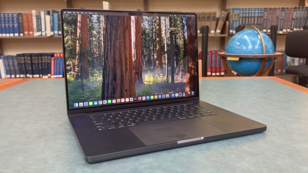 Apple MacBook Pro 16-inch on a table with bookcase in the background