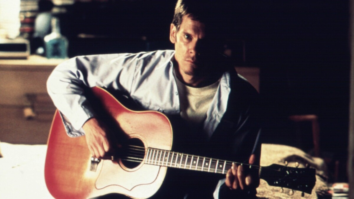 Kevin Bacon holds a guitar in "Stir of Echoes."