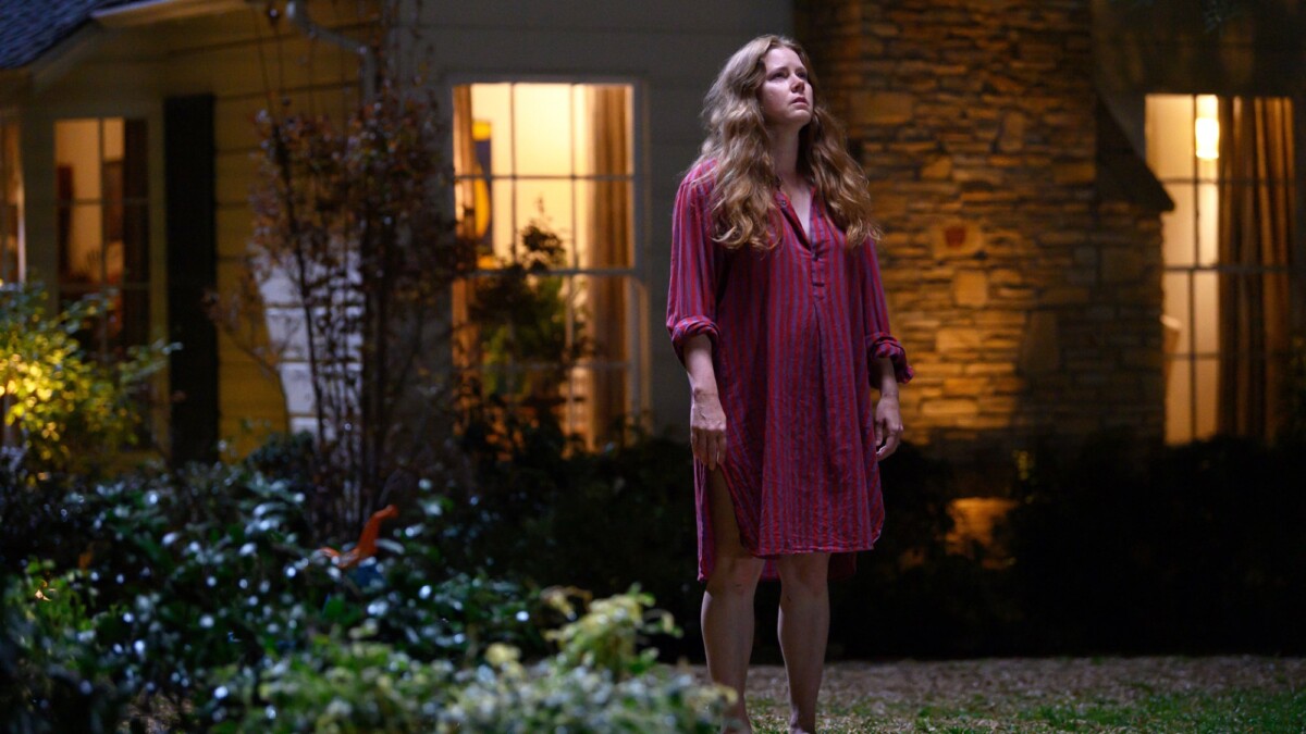 Amy Adams as Mother in "Nightbitch," standing outside her house.