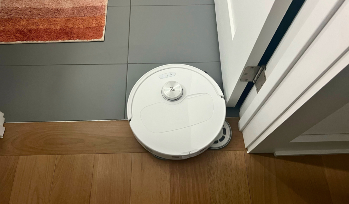 Roborock Qrevo Master robot vacuum mopping corner of tile floor with rug in background