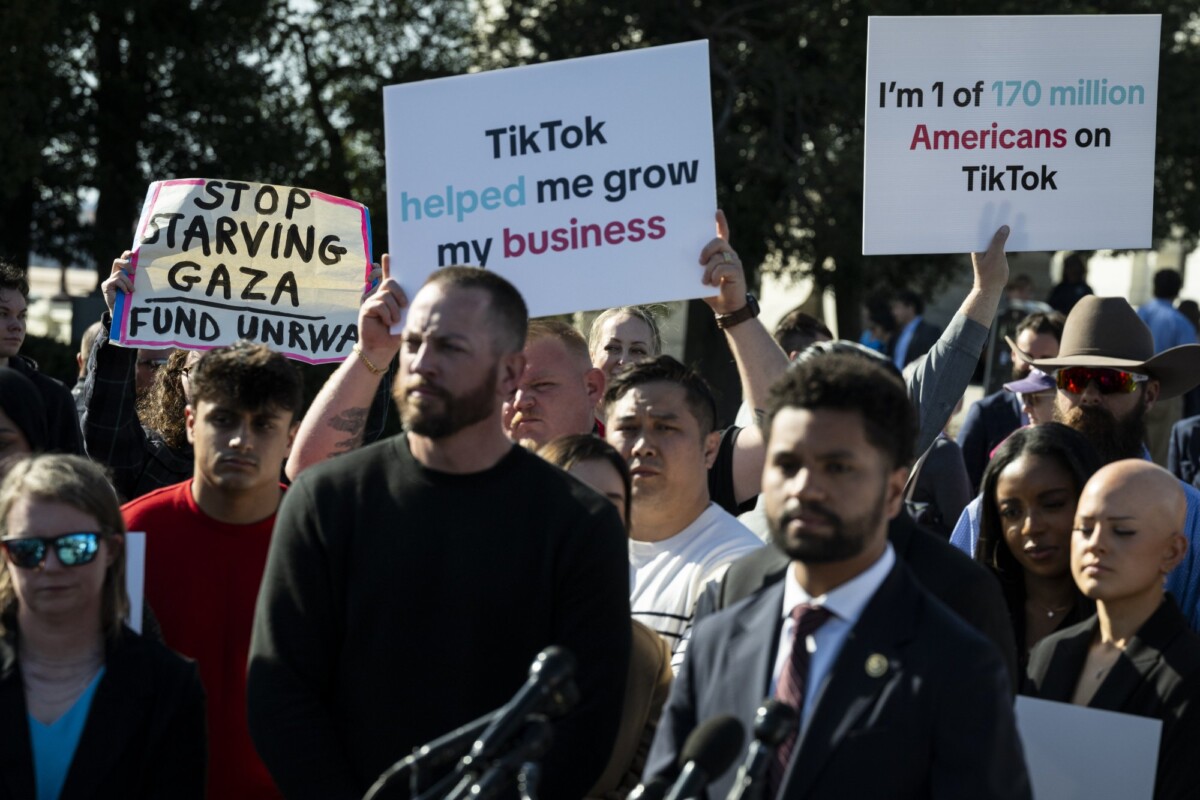 A crowd behind Congressman Maxwell Frost hold up signs that read "Stop starving Gaza. Fund the UNRWA." "TikTok helped me grow my business" and "I'm 1 of 170 million Americans on TikTok."