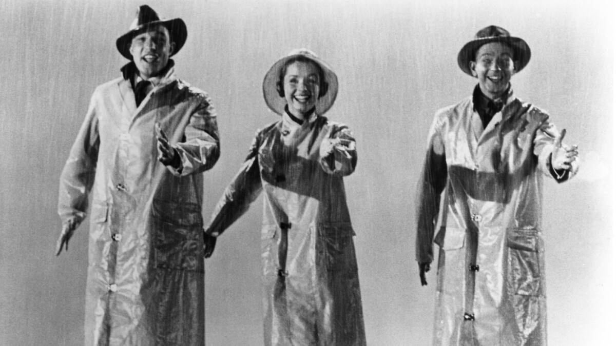 Gene Kelly, Debbie Reynolds, and Donald O'Connor dance in rain slickers.