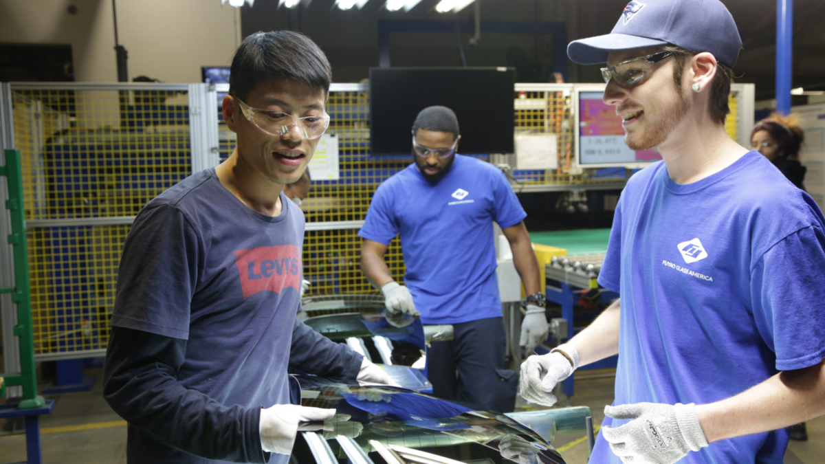 Men wearing blue work in a factory. 