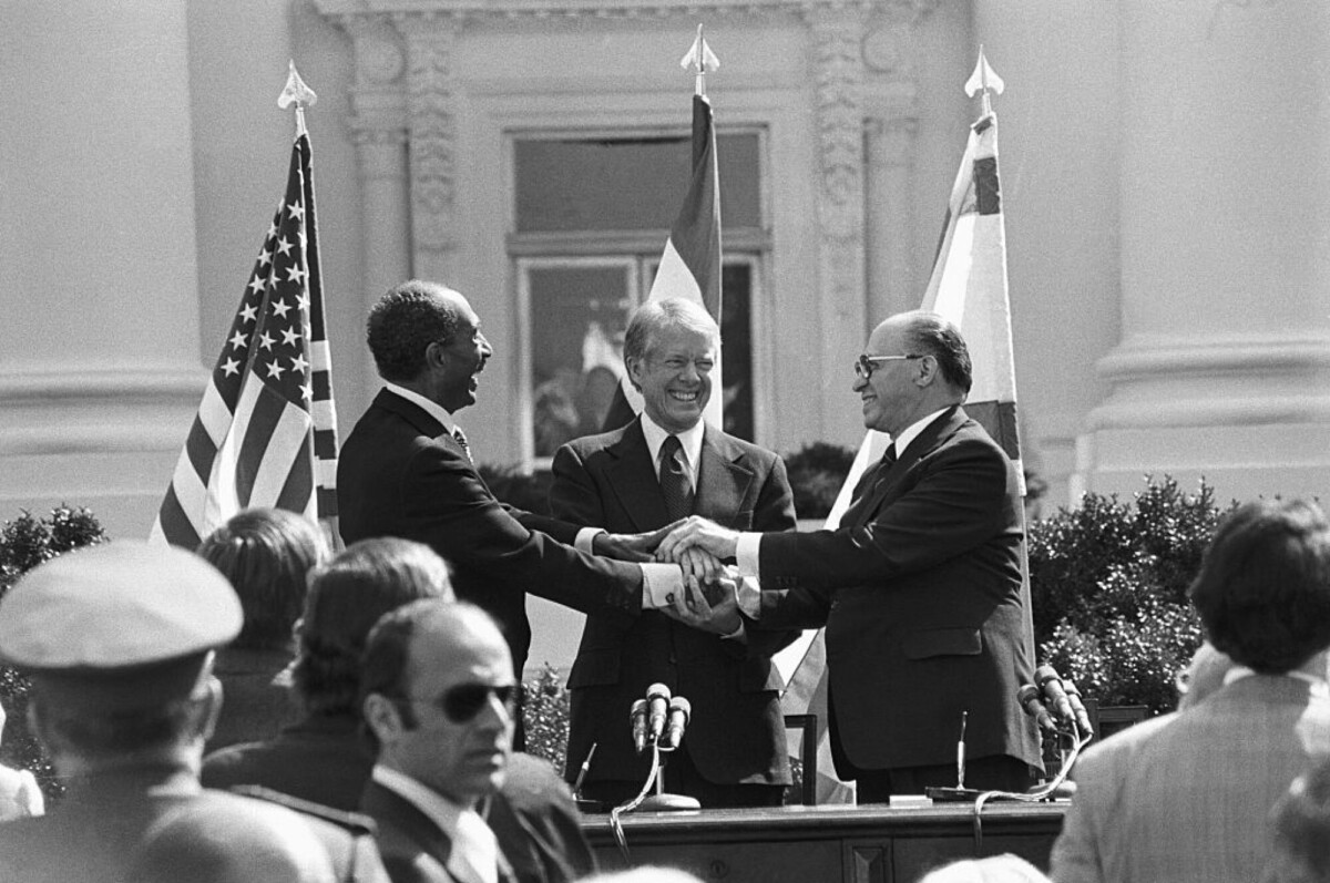 President Jimmy Carter, Anwar Sadat and Menachem Begin share a three-way handshake after signing Camp David Accords.